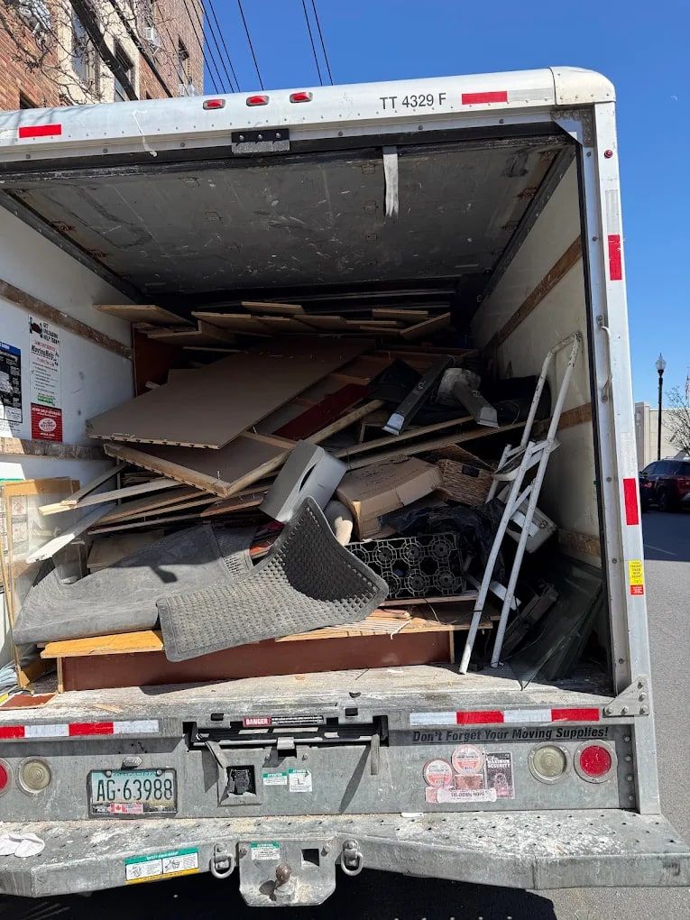 Box truck filled with flattened cardboard, old carpet and metal shelving from a cleanout