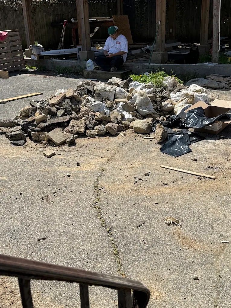 Pile of broken concrete rubble and bags in a yard before debris removal