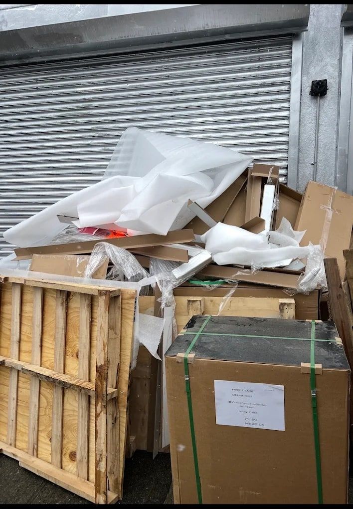 Wooden crates and cardboard packaging piled at a roll-up garage door, ready for junk removal