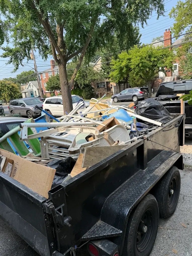 Dump trailer piled high with furniture and household junk, loaded by the Mitzvah Movers & Junk Removal crew