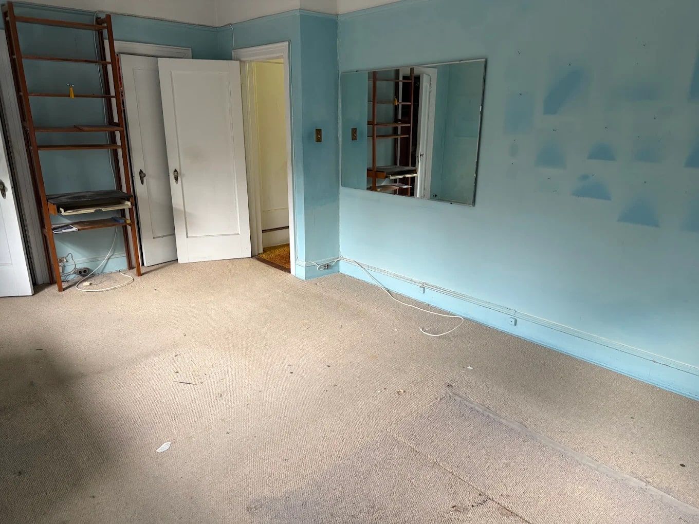 Empty bedroom with blue walls and bare carpet after an estate cleanout