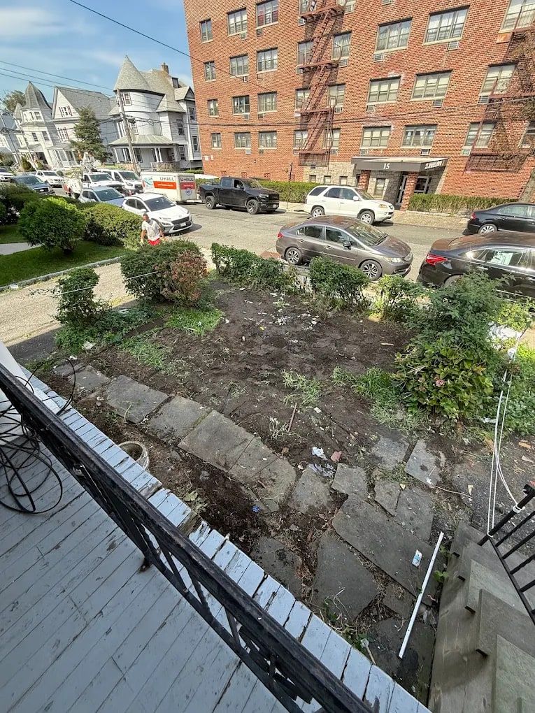 Small front garden bed cleared of debris, seen from a porch on a residential street
