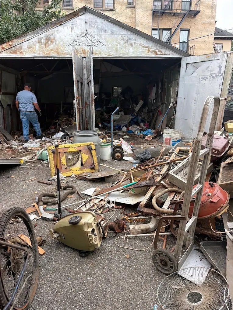 Before a garage cleanout: detached garage with scrap metal, an old bike and debris spilling onto the driveway