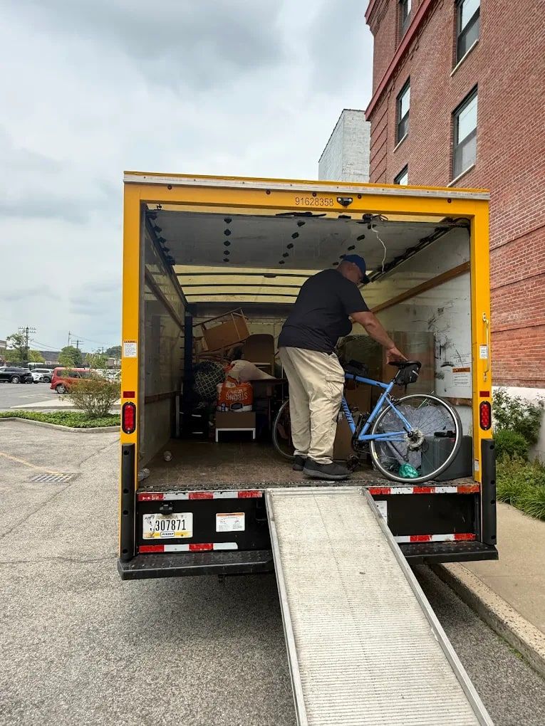 Mover rolling a bicycle up the ramp into a box truck while loading for a move