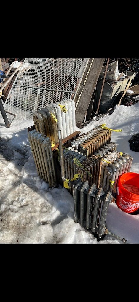 Old cast-iron radiators lined up in the snow, ready to be hauled away