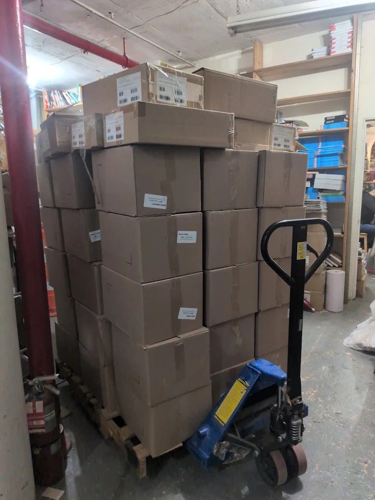 Pallet of packed cardboard boxes with a pallet jack, ready to be loaded for a move