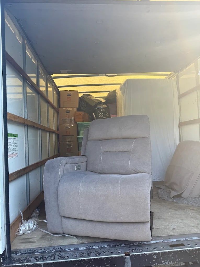 Gray recliner loaded into the back of a box truck during a furniture removal job by Mitzvah Movers & Junk Removal