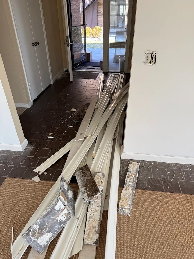 Torn-out wood trim and drywall pieces stacked in a hallway after a renovation