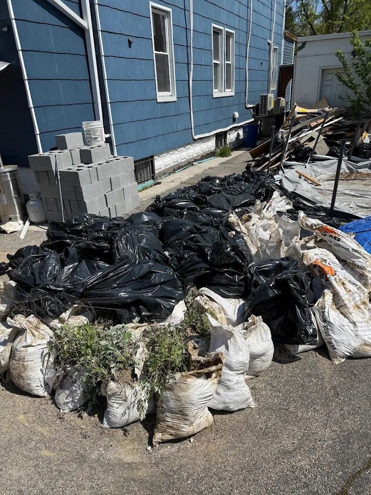 Bags of yard debris, sandbags and cinder blocks piled beside a house for removal